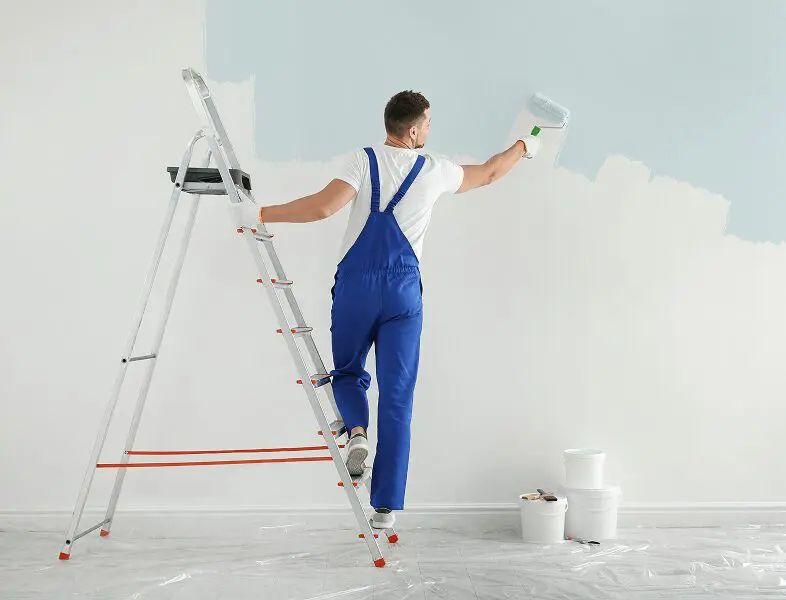 Painter applying blue paint on wall